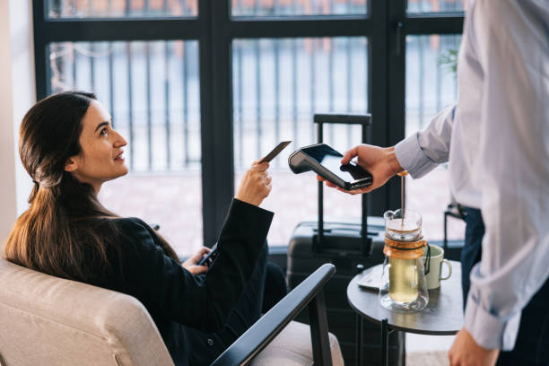 Businesswoman paying with credit card at airport business lounge Businesswoman pays for her tea using contactless payment in the airport VIP lounge contactless airport stock pictures, royalty-free photos & images