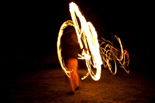 Dynamic fire dancer at night. A slow shutter has captured a great circle of fire with some intricate patterns and good sense of movement.