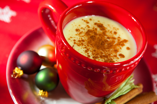 Egg nog with cinnamon and holiday Christmas ornaments.  Shallow depth of focus on cinnamon.