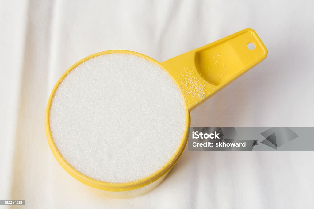 Sugar in Yellow Measuring Cup One cup of white granulated sugar in a yellow measuring cup. Baking Stock Photo