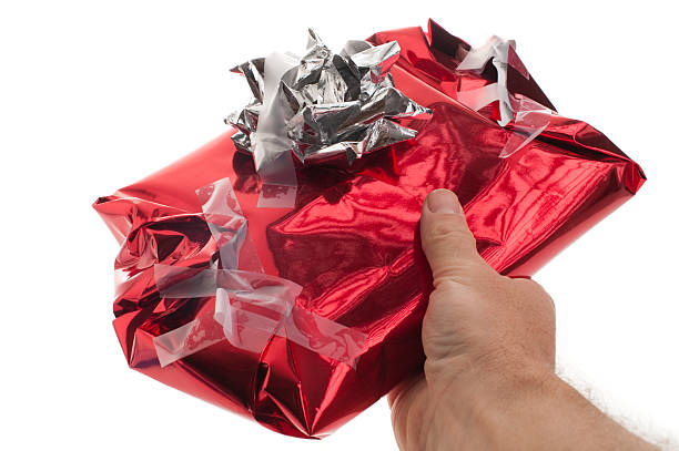 Man gives badly wrapped, messy Christmas present "Man gives badly wrapped, messy Christmas present" wrapping paper photos stock pictures, royalty-free photos & images