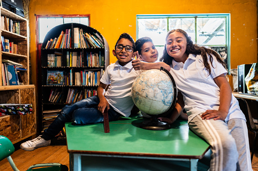 Portrait of child friends students with globe in the library