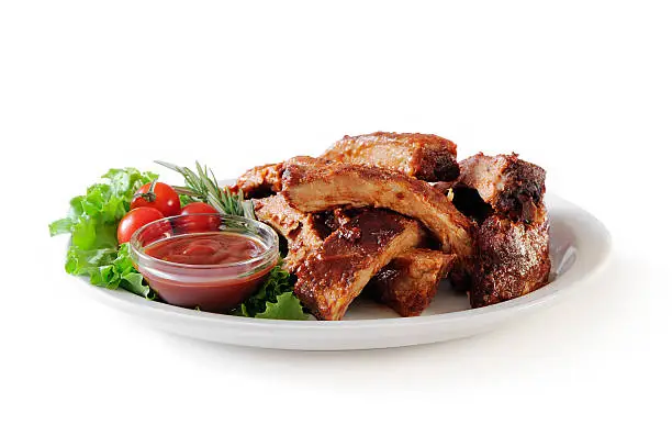 "Plate of cut baby back ribs with barbecue sauce,lettuce and cherry tomatoes isolated on white. More ribs..."