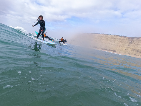 Young woman surfs perfect waves with surf school, Algarve