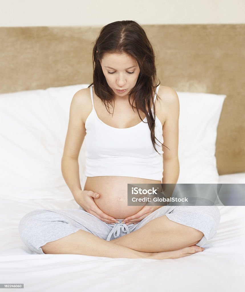 持つ女性彼女の妊娠中のお腹をベッド - 1人のロ�イヤリティフリーストックフォト