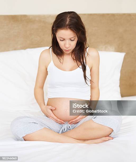 Kobieta W Ciąży Trzymając Jej Brzuch W Łóżku - zdjęcia stockowe i więcej obrazów 20-24 lata - 20-24 lata, 20-29 lat, Antycypacja