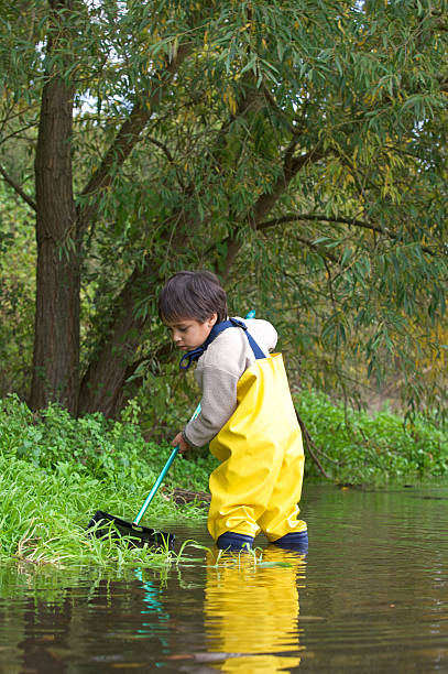 istock Young boy and his net fishing in a stream 182246588