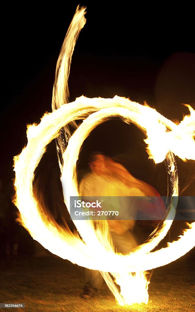 Dynamic fire dancer at night Dynamic fire dancer at night. A slow shutter has captured a great circle of fire touching the ground with some intricate patterns and good sense of movement. Flame Stock Photo