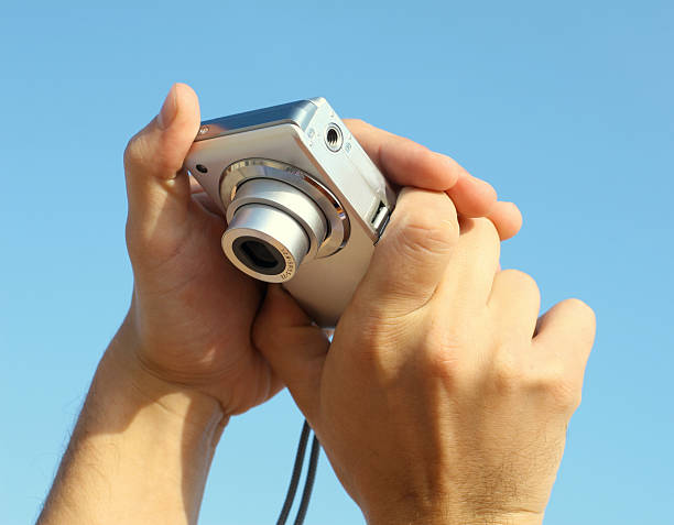 istock photocamera in hand over a blue sky 182247033