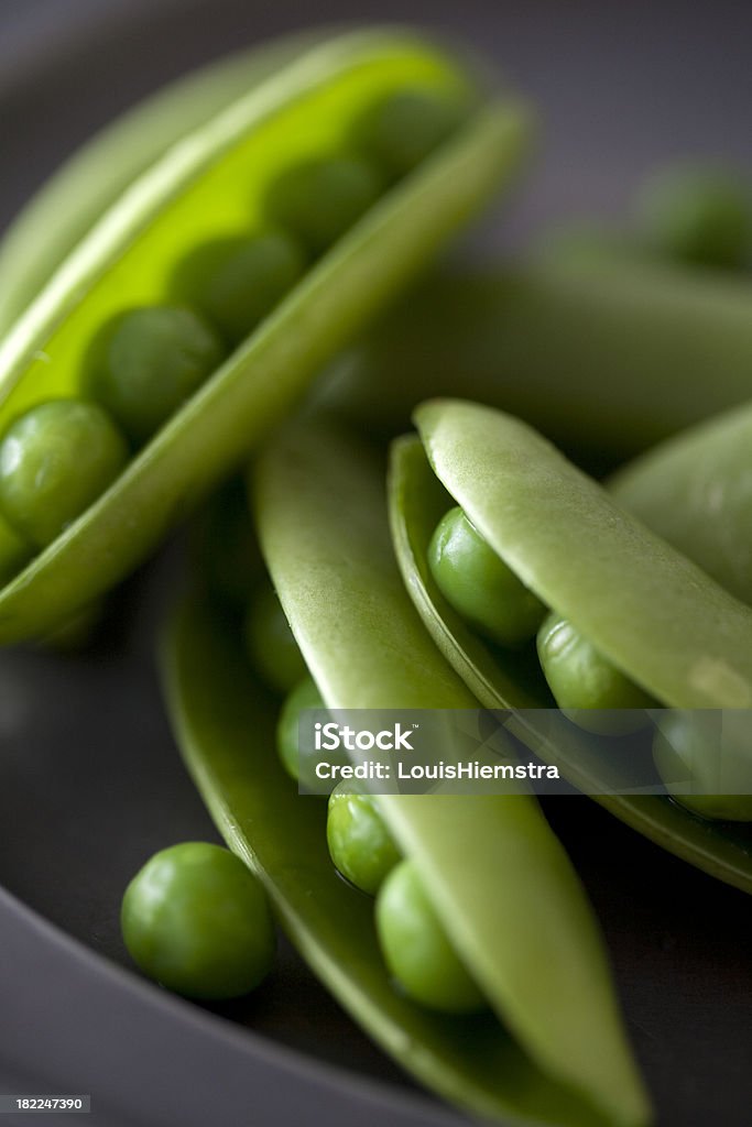 Peas "Sweet ripe sugarsnap peas in the pod, on a dark plate." Food Stock Photo