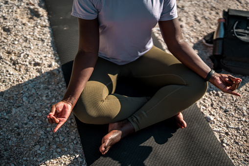 Close up on a leap of a Black female sitting in a lotus position meditating by the river.