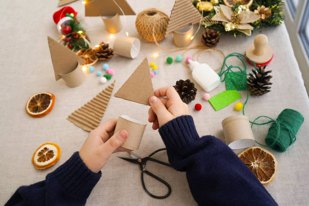 istock Step-by-step instructions on how to make a Christmas tree out of cardboard. Step 2 connect the upper triangular part with a cardboard roll stand. Zero waste concept. 1822487003