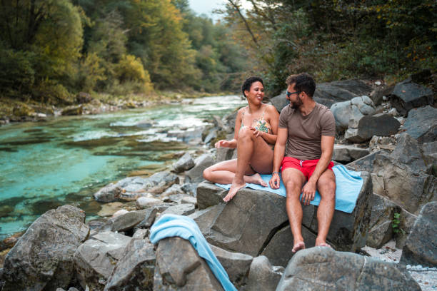 Mid adult multi-ethnic couple taking and enjoying a relaxing day by the river. They are wearing swimsuits.