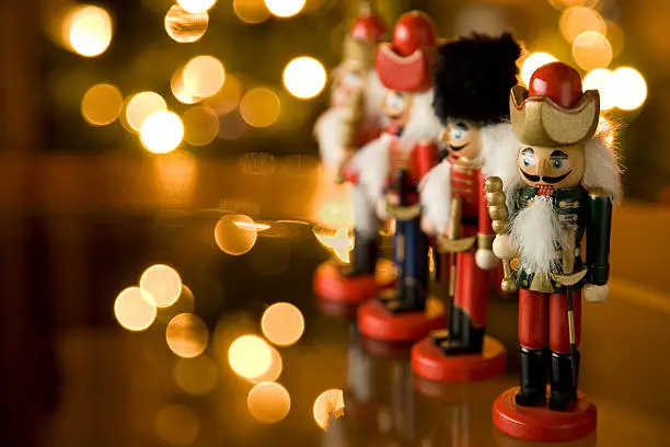 Nutcrackers on a glass table with out of focus christmas lights in the background.