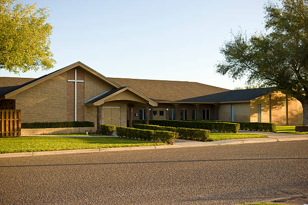 Long view of the front of a brown brick church with a cross typical modern christian church facade with large cross in front evangelic stock pictures, royalty-free photos & images