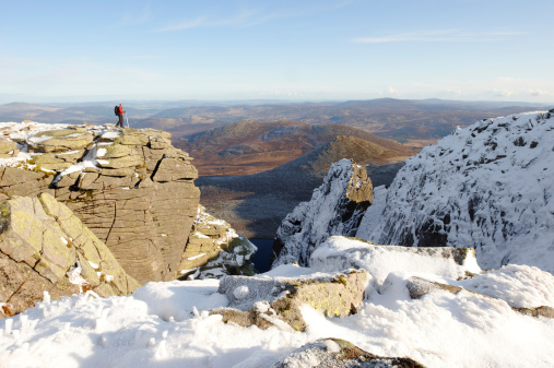 A walker on the cliffs above the north face of Lochnagar. Royal Deeside is in the background.