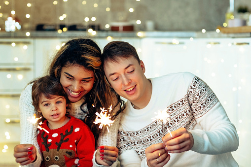 Portrait of multiethnic family holding Christmas sparklers and celebrate New year at their home