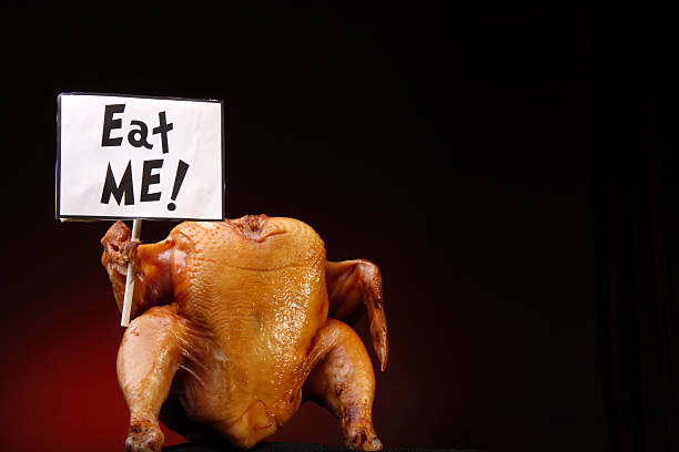 A headless cooked turkey holding a sign that says eat me  stock photo