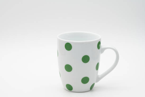 White ceramic mug for coffee, tea or milk with green dots isolated on a white background