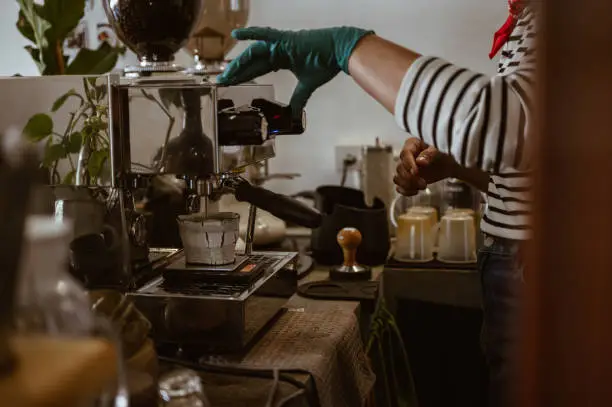 Photo of Cropped shot view of Barista hand using Espresso machine to making espresso coffee shot.