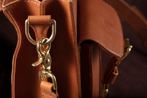 Part of a bag made of brown genuine leather with a metal fastening for the handle.