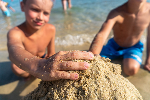 two boys are building a sandcastle by the water on the beach