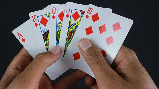 Hand with poker cards isolated on dark background