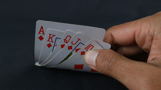 Hand with poker cards isolated on dark background