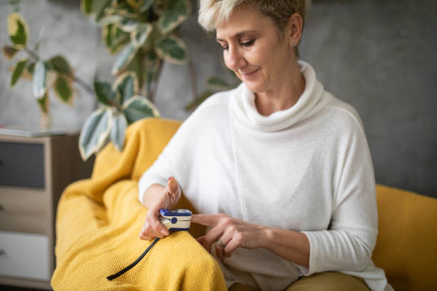 женщина с помощью пульсоксиметра в домашних условиях - taking pulse oximeter medical oxygen equipment human lung стоковые фото и изображения