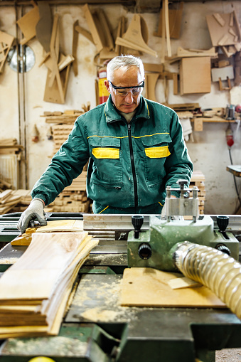 Carpenter sands wooden board in furniture factory