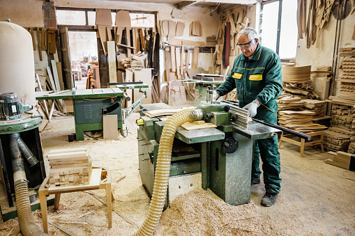 Technician in furniture workshop processes wood