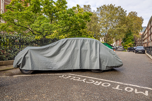 The Temple, London, England - October 25th 2023: Classic car under a tarpaulin in a quiet corner in the Temple district in the center of the English capital