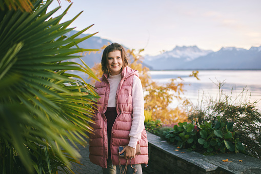 Outdoor portrait of beautiful young woman relaxing by mountain lake, cold weather