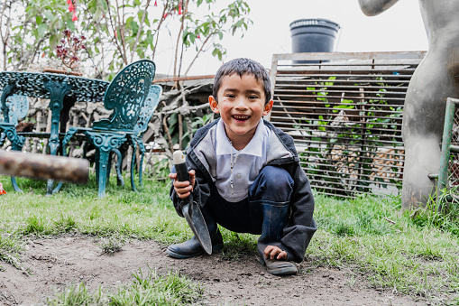 Portrait of a child boy playing digging dirt in the school garden
