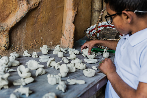 Child boy organizing small clay sculptures at school art studio