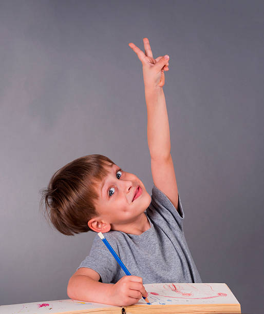 istock schoolboy raising his hand 182262429