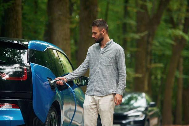 istock Young man is putting charger into the socket of electric automobile 1822641349