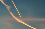 Airplane flying with condensation trails or contrail on the sky in the sunset