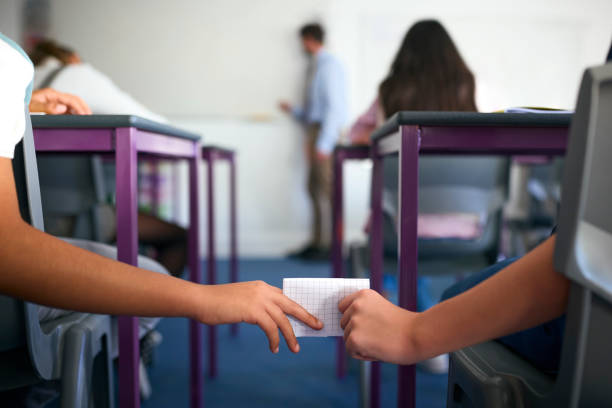 istock Close Up Of Two Male Secondary Or High School Pupils Passing Note During Lesson 1822665932