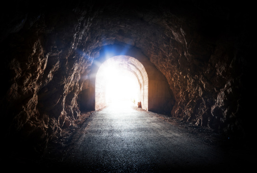 End of dark tunnel with magic blue light from the outside