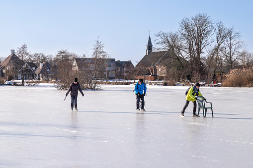 Tienhoven, Netherlands, February 12, 2021; Woman tries to learn to skate on the ice with a chair.