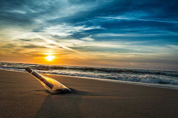 nachricht in der flasche mit einem buchstaben auf einem strand - document paper paperwork buried stock-fotos und bilder