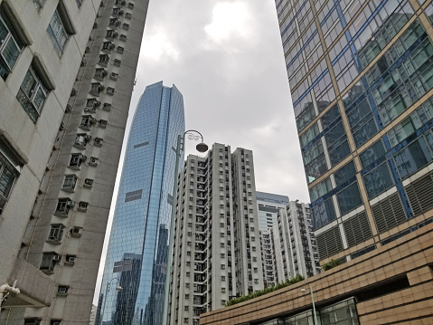 Multiple high-rise office and residential towers cover most of a cloudy sky in Hong Kong's Kowloon section