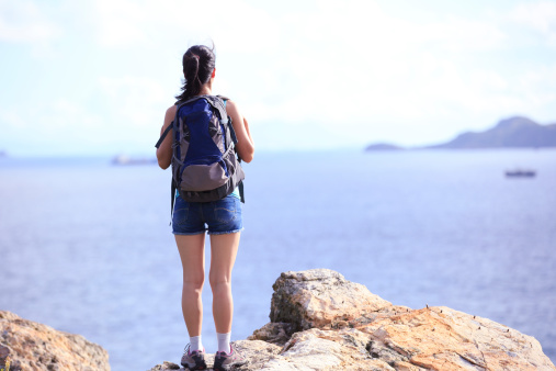 young asian woman hiker stand seaside rock