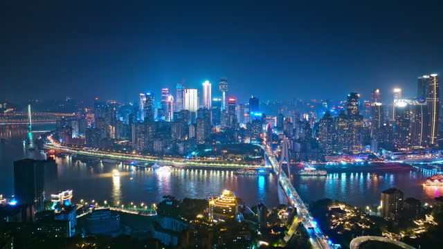 Aerial shot of city buildings skyline and river at night in Chongqing, China