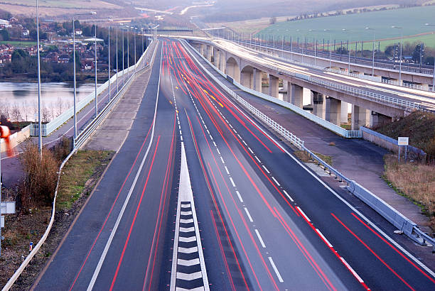 Vehicle light trails Trails of light made by vehicles travelling at dusk on a motorway in England UK. The photograph has been taken when there is still plenty of light but with a long exposure to create an unusual image. m2 machine gun photos stock pictures, royalty-free photos & images