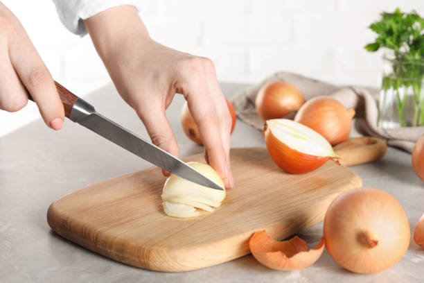 istock Woman cutting ripe onion at grey textured table, closeup 1822761764