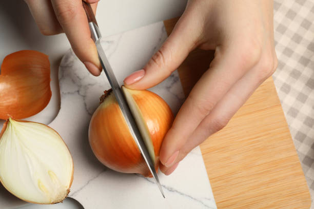 istock Woman cutting ripe onion at white table, top view 1822763466