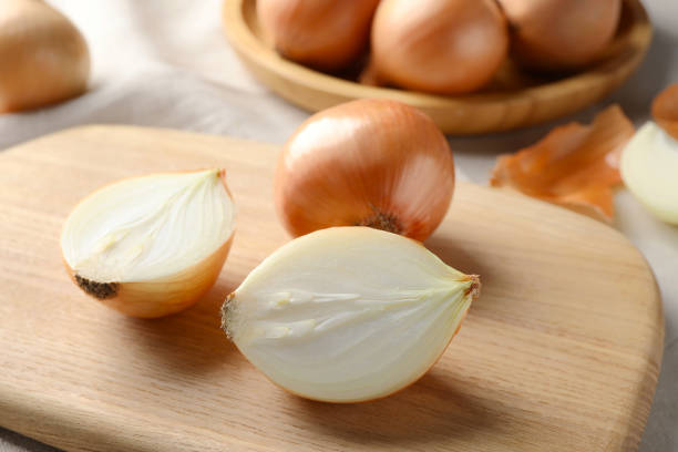 istock Whole and cut onions on wooden board, closeup 1822763472