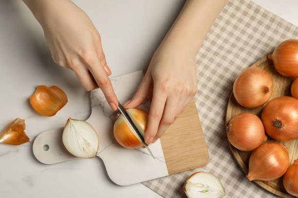 istock Woman cutting ripe onion at white marble table, top view 1822763476